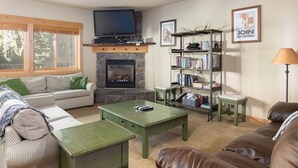 Un salon confortable avec une cheminée, un téléviseur, une bibliothèque et un canapé en cuir.