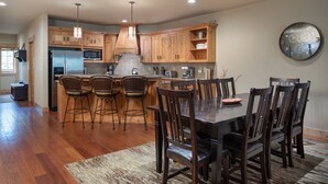 Una cocina amplia con armarios de madera, una isla central con taburetes de bar y una mesa de comedor con sillas.