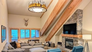 A cozy living room with a stone fireplace, a large TV mounted above it, and a modern sofa set.