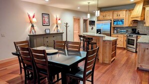 Una cocina moderna con armarios de madera, un comedor con mesa de vidrio y una isla integrada con asientos.