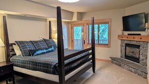 Un dormitorio con una cama con dosel, una chimenea de piedra y un televisor sobre la repisa.