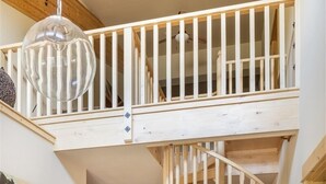 Ein großzügiges Loft mit einer Holztreppe, einem Essbereich und einer Küche.