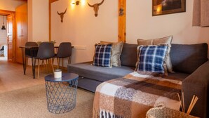 A cozy living room with a sofa, a coffee table, and a dining area with chairs. - Riverfront Retreat by Grandvalira & Parking

 (Canillo)