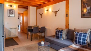 A cozy living room with a sofa, a dining table with chairs, and a small round table with a candle. - Riverfront Retreat by Grandvalira & Parking

 (Canillo)