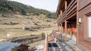 A wooden building with a stone staircase leading to a porch overlooking a valley with scattered houses and a mountain in the background. - Riverfront Retreat by Grandvalira & Parking

 (Canillo)