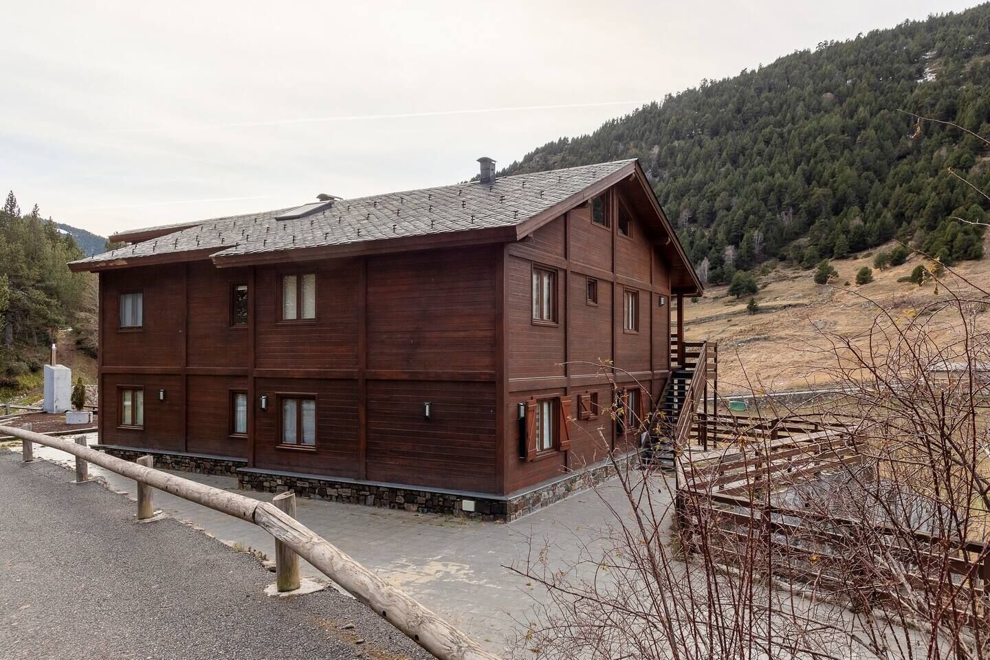 Un bâtiment en bois à plusieurs étages, doté d’un toit en pente, situé dans une région montagneuse sous un ciel dégagé.
