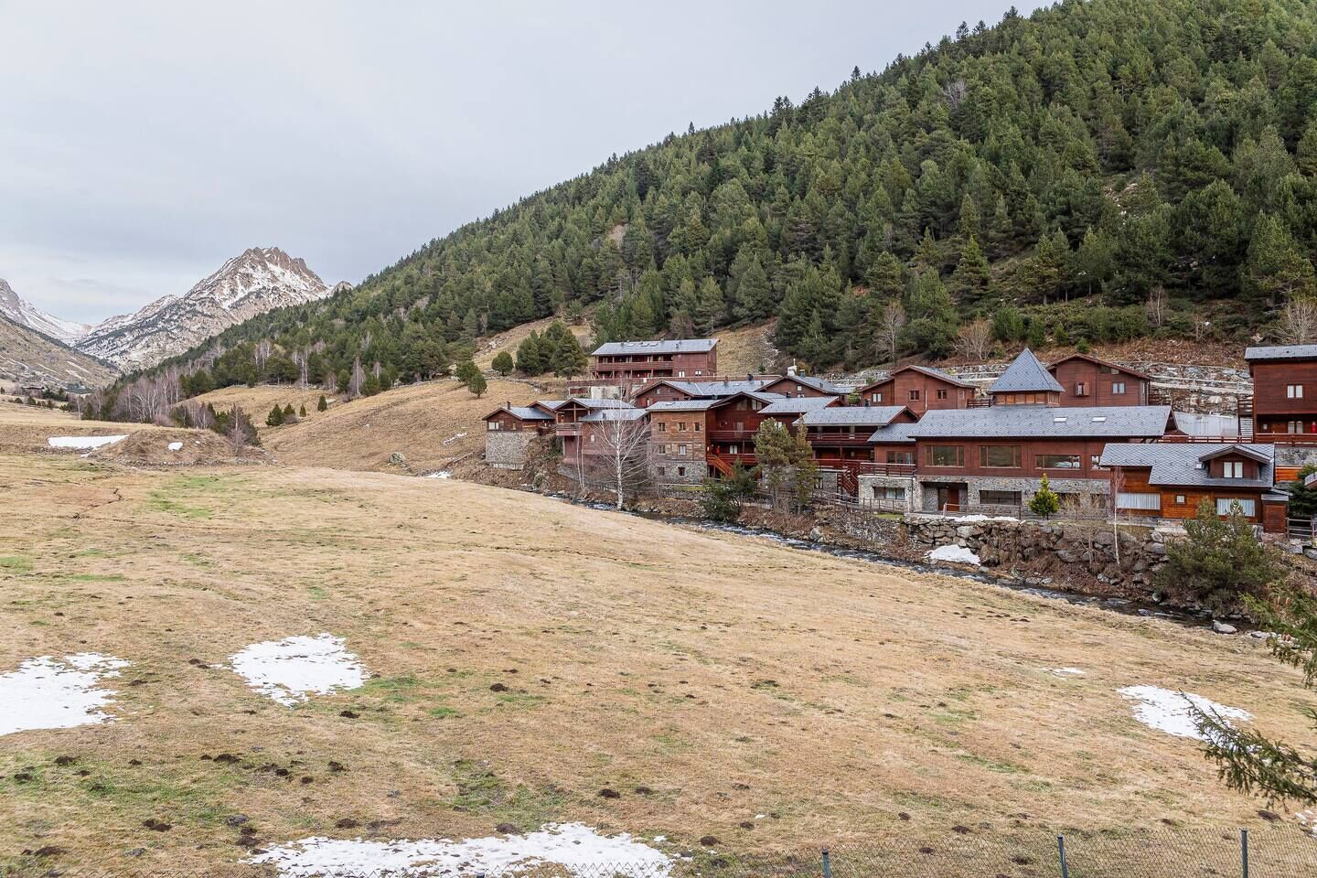 Un grupo de cabañas de madera con montañas al fondo.