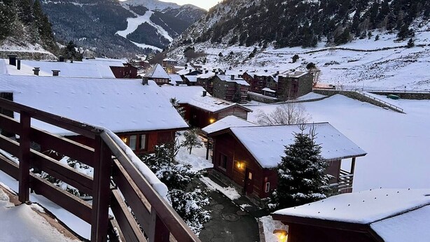 A snow-covered mountain village with wooden buildings and a wooden bridge. - Riverfront Retreat by Grandvalira & Parking

 (Canillo)
