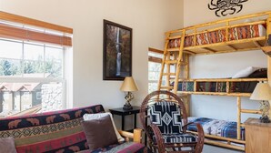 Una habitación acogedora con sofá, una silla, una escalera y una cama litera.