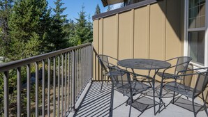 Ein Balkon mit Metallgeländer, einem runden Tisch und vier Stühlen.