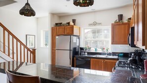Una cocina con armarios de madera, un refrigerador de acero inoxidable, una estufa y una cafetera.