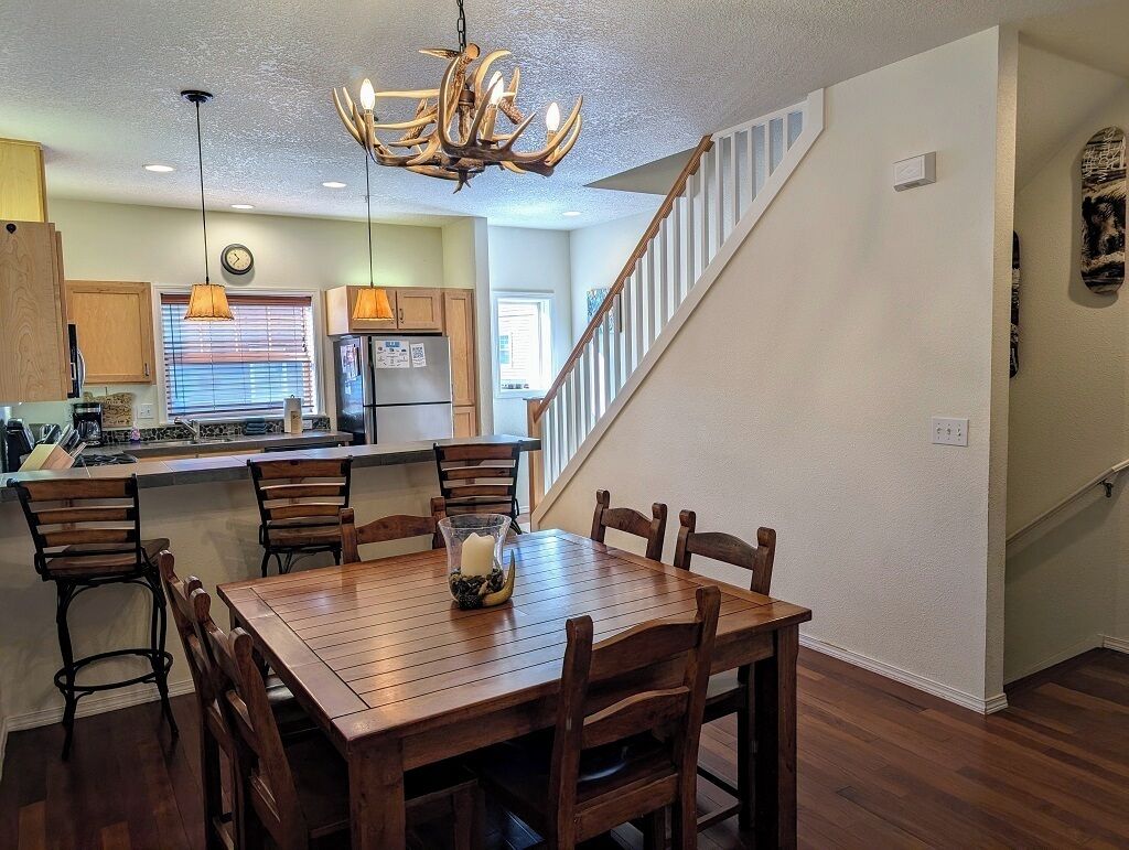 A modern kitchen with wooden cabinets, a central island, and a dining area with a wooden table and chairs.