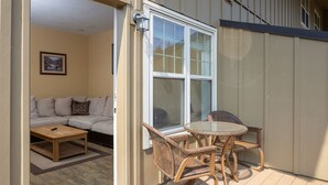 A cozy patio with wicker furniture, a cushioned sofa, and a glass table. - Chalet 135 at the Official Collins Lake Resort (Government Camp)