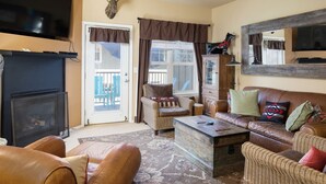 Un salon chaleureux avec une cheminée, des meubles en osier et un grand miroir.