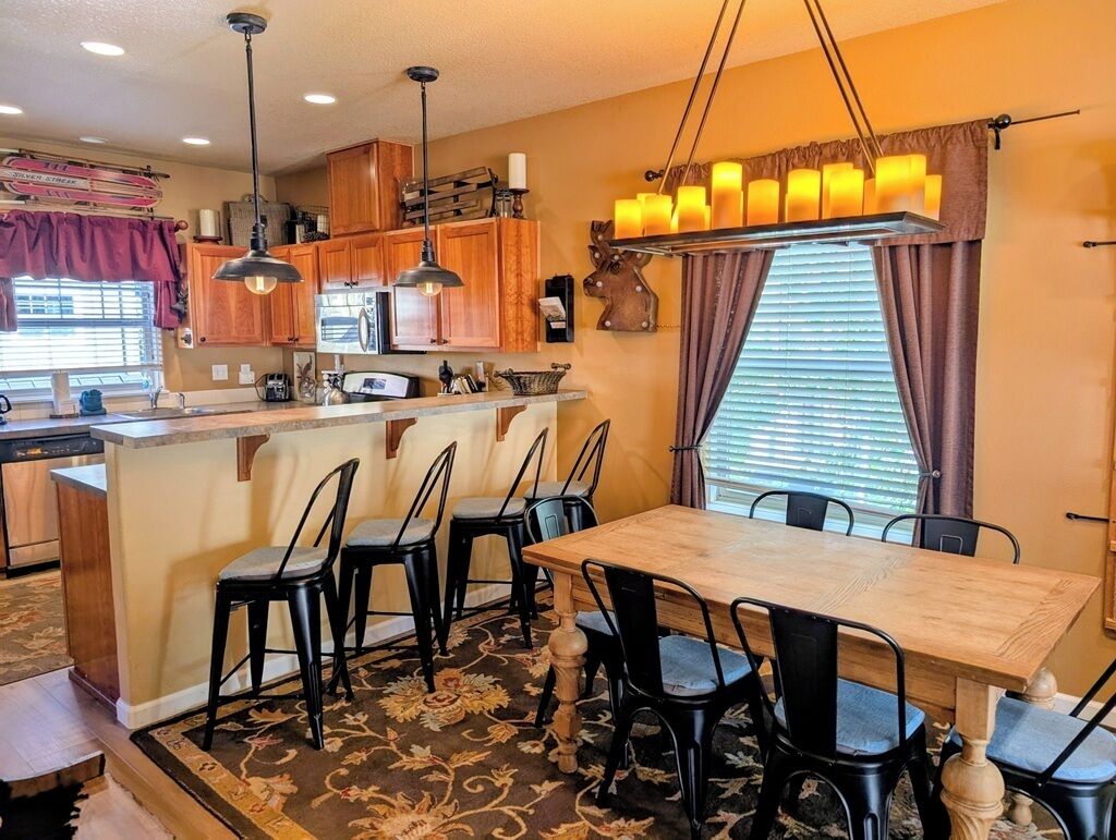 A compact kitchen with wooden cabinets, a central island, and a dining area with a table and chairs.