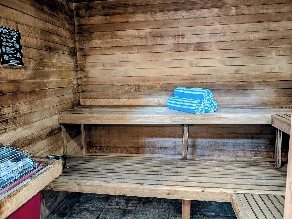 A sauna with wooden benches and a stack of towels.