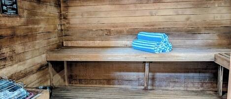 A sauna with wooden benches and a stack of towels.