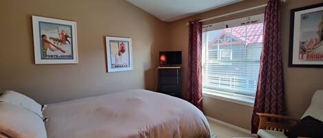 A bedroom with a bed, a chair, a TV, and two posters on the wall.