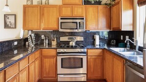Una cocina con armarios de madera, estufa de acero inoxidable, microondas y un lavaplatos.