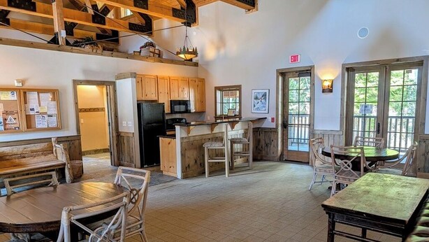 Un intérieur rustique avec des meubles en bois, un coin cuisine et un espace salon avec des tables et des chaises.