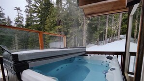 A hot tub on an outdoor deck with a view of a snowy forest. - Slope Side Cabin at the Official Collins Lake Resort (Government Camp)