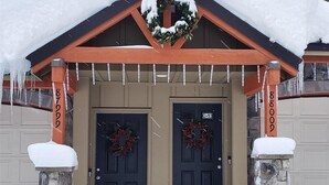 A snow-covered entrance with two doors, each adorned with a wreath.