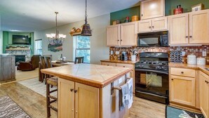 A kitchen with wooden cabinets, a central island, a microwave, and an oven. - Chalet 106 at the Official Collins Lake Resort (Government Camp)