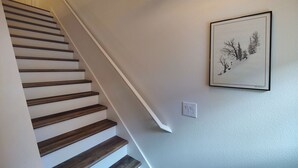 A staircase with wooden steps and a white wall. There is a framed picture on the wall. - Chalet 32 at the Official Collins Lake Resort (Government Camp)