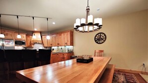 Une cuisine moderne avec des meubles en bois, un grand îlot central, des luminaires suspendus et une horloge murale décorative.