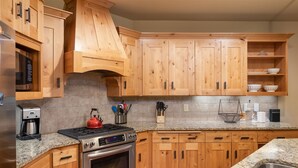 Una cocina con armarios de madera, un horno de acero inoxidable, una cafetera y un hervidor.