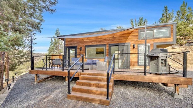 A modern house with a wooden exterior, a deck, and a barbecue area.