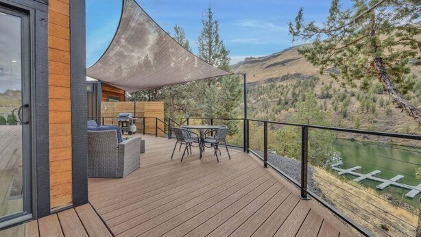 A wooden deck with outdoor furniture, a large umbrella, and a view of a river and mountains. - Lake Simtustus Resort Juniper Hill Tiny Home #11 - Hot Tub (Madras)