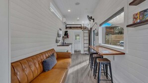 A compact kitchen with a wooden countertop, a built-in bench, and a ladder leading to a lofted sleeping area. - Lake Simtustus Resort Juniper Hill Tiny Home #11 - Hot Tub (Madras)
