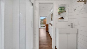 A modern bathroom with white cabinetry, a wooden floor, and a view of a mountain landscape through a large window.