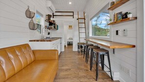 A modern kitchen with white cabinetry, a wooden countertop, and bar stools.