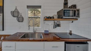 A modern kitchen with a wooden countertop, stainless steel sink, and a built-in dishwasher.