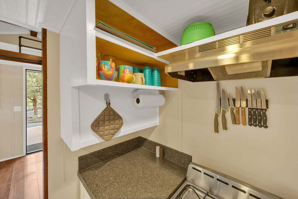 A compact kitchen with a granite countertop, a stainless steel sink, and a variety of knives and kitchen utensils.