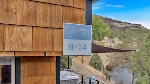 Pared exterior de madera con un letrero que indica 'Juniper Hill' y 'B-14'.