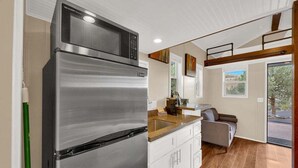 Una cocina moderna con un refrigerador de acero inoxidable, armarios blancos y encimera de madera.