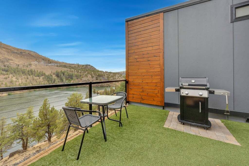 A balcony with artificial grass, a table and chairs, and a grill.