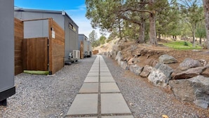 Un sentier mène à une rangée de cabanes, avec un chemin de gravier et une clôture en bois d’un côté.