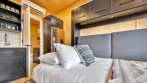 Une chambre moderne comprenant un lit, une armoire intégrée et un coin cuisine.
