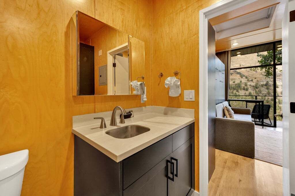A modern bathroom with a wooden wall, a sink, and a mirror.