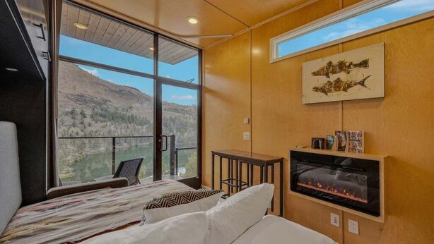 Une chambre avec une grande fenêtre, une cheminée et une vue sur les montagnes.