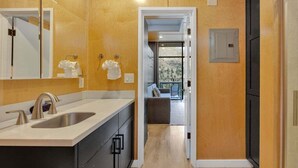 Un baño moderno con un lavamanos grande, espejo y perchero.