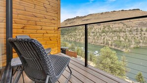 Un balcón con sillones de mimbre y vistas a un río y colinas.