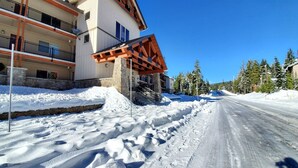 Una carretera nevada con un edificio de fachada de piedra y vigas de madera.