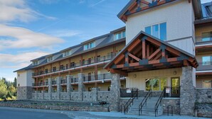 Un hotel de varios pisos con fachada de piedra, balcones y una entrada destacada con escaleras.