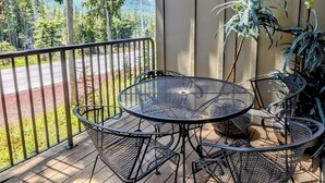 Een balkon met een ronde metalen tafel en stoelen, omgeven door potplanten.