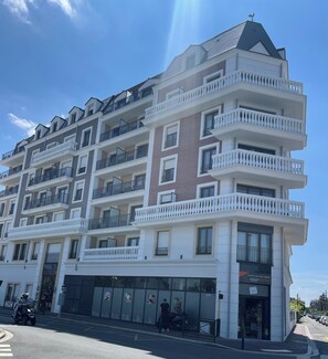 A multi-story building with balconies, a storefront, and a clear sky.